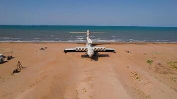 Old plane on beach. Action. Military plane landed on coast of sea many years ago. Abandoned military plane on seashore with history video