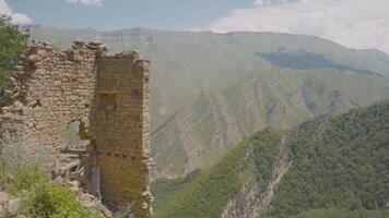 Stone ruins on background of green mountains on sunny day. Action. Ruins of ancient castle over mountain valley. Stone ruins in green Mountains video