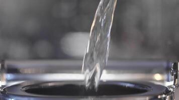 Close-up of water being poured into metal kettle. Action. Stream of clean water is poured into kettle. Water is poured into metal teapot for tea video