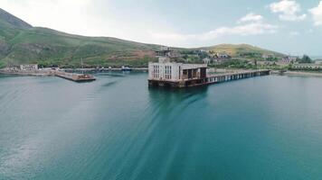 Abandoned factory with pier on coast. Shot. Beautiful pier with abandoned factory building or fishing enterprise. Secret abandoned factory for production of torpedoes in Crimea video