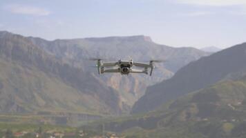 Quadcopter flies on background of mountains. Action. View of quadrocopter flying in air on background of mountains. Quadcopter takes pictures of mountain landscapes on sunny day video