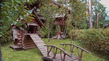 detalhes do uma verão parque com tradicional russo conto de fadas de madeira casas cercado de verde gramado e árvores . uma cabana em frango pernas ou baba yaga cabana dentro eslavo folclore. video