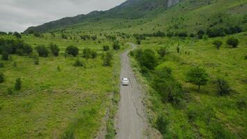 Top view of car driving on road near green mountains. Action. Beautiful car ride through mountain places. Single car is driving on road on background of green mountains video