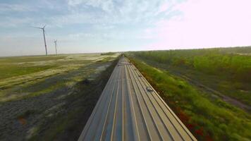 Top view of freight train on green field background. Shot. Drone follows train at speed. Train rides with load on railway on background of green field on sunny day video