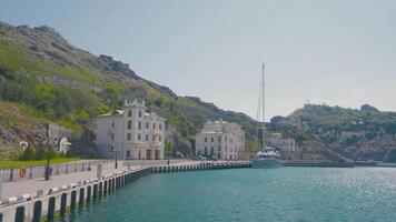 Old town on mountain coast on sunny day. Action. Beautiful beach with old houses of southern city. Sea tourist city on background of green mountains and bright sun video