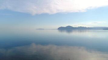 Flying over mirror water on background of mountains. Shot. Picturesque view of sea surface with reflection of blue sky. Mountain coast on horizon near mirror water video