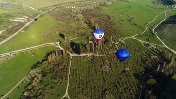 antenne visie van kleurrijk ballonnen in de lucht over- de platteland Oppervlakte, Frankrijk. schot. vliegend bovenstaand bomen, struiken, groen velden, en park auto's. video