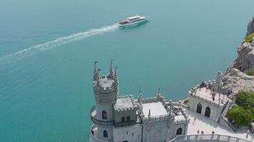 oben Aussicht von Schloss auf Kante von steil Cliff. Aktion. schön Weiß Schloss ist gelegen über felsig Cliff in der Nähe von Blau Meer. Schwalbe Nest Schloss auf Ufer im Krim video