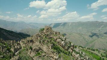 antiguo Roca ciudad en rock en antecedentes de montañas. acción. increíble asentamiento de rock casas en parte superior de montaña. atracción de daguestán - pueblo de fantasma en montañas video