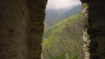 Beautiful view of mountains from window of ruins. Action. Stone arch from ruins with view of green mountains. Green mountains from ruins window video
