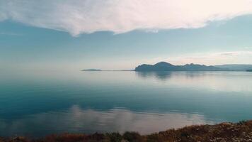 Flying over mirror water on background of mountains. Shot. Picturesque view of sea surface with reflection of blue sky. Mountain coast on horizon near mirror water video