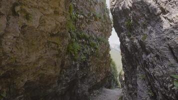 eng Passage im Felsen. Aktion. gefährlich eng Schlucht zwischen zwei Felsen. eng Passage unter Berg Felsen mit Moos video