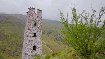 Stone towers of ancient buildings in mountains. Action. Old stone tower on background of green mountains. Preserved tower of ancient structure in mountains video