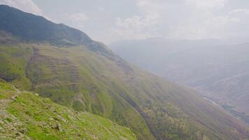 Green mountain valley with rocks in haze. Action. Top view of valley in misty mountains. Morning fog in mountain valley on sunny day video