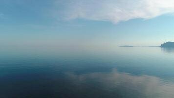 bellissimo riflessione di blu cielo nel specchio acqua. sparo. pittoresco paesaggio marino con riflessione di cielo nel mare su sfondo di montagne. mattina blu cielo è riflessa nel acqua superficie video