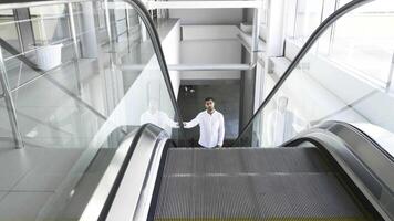 Mens in een wit overhemd gaan omhoog de roltrap binnen de bedrijf centrum. hdr. jong Mens Aan de roltrap Bij de afdeling op te slaan. video