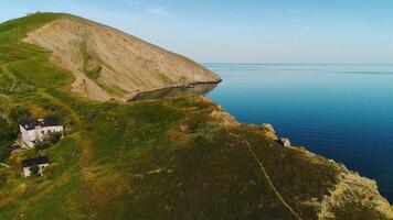 Haut vue de rocheux cap sur Contexte de bleu mer. tir. éloigné la vie dans maison sur mer cap. magnifique paysage de Maisons sur vert cap sur Contexte de mer horizon video