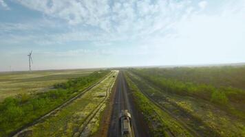 Top view of moving train on horizon background. Shot. Slow moving train on rails with beautiful view of green fields and trees. Beautiful landscape with train going to horizon video