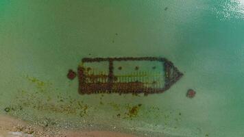 Overgrown sunken ship. Shot. Top view of sunken ship with algae. Sunken ship stuck in sand and overgrown with algae on coast video