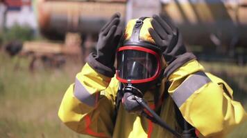 homem ajustando uma gás mascarar. grampo. a empregado quem é vestindo uma gás mascarar e uma amarelo terno é a ao ar livre trabalhador quem é caminhando a partir de atrás video