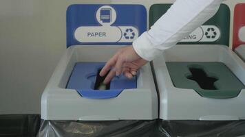 Throwing a piece of paper in a special bin for waste recycling, concept of ecology. HDR. Close up of male hand putting a small sheet of paper in a recycling bin. video