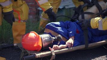 zuerst Hilfe im ein unsicher Bereich. Clip. ein Mann im ein Gas Maske auf ein Bahre Wer ist Sein geholfen durch seine Gas Maskentragend Partner. video