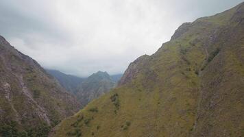 Aerial view of a picturesque gorge on heavy cloudy sky background. Action. High mountains covered by green summer lush forest. video