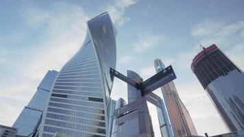 Bottom view of a twisted skyscraper on blue cloudy sky background. Action. Glass facade tall buildings in the business city center. video