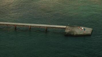 ein lange Brücke Über das Meer. das Aussicht von das Drohne. kreativ. ein Blau wellig Meer mit ein lange Brücke Über es wo Menschen entspannen nehmen Bilder und schwimmen video