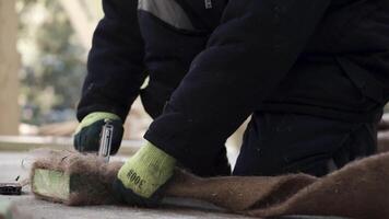 om de golv. klämma. en man gör en särskild fiber för isolering av golv i hus med en häftapparat. video