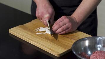stänga upp av man händer skärande vit lök på en trä- hackning styrelse med en kök kniv. konst. framställning friska mat. video