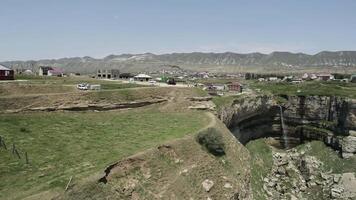 aéreo ver de un pequeño pueblo situado por el borde de un escarpado acantilado. acción. vivo en el campo en montañas, concepto de ecología. video