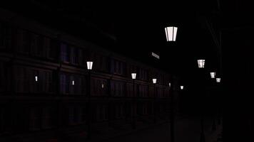 resumen ciudad paisaje con un vacío calle decorado por dos filas de linternas diseño. antiguo pasado de moda edificio y un Moviente tren con luces en ventanas Moviente encima el casa a noche. video