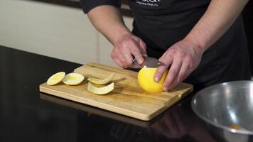 Close up of a male chef peeling a fresh orange fruit with a steel knife on a wooden board. Art. Concept of vegan food, vitamins, and cooking. video