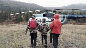 A helicopter taking off . Clip. People walking to a helicopter in a cool forest video