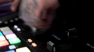 dj mãos com tatuagens toque botões e controles deslizantes, jogando eletrônico música. arte. conceito do festa, noite clube e techno música. video