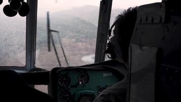 das Pilot ist fliegend im ein Hubschrauber. Clip. ein Mann Kontrollen ein Hubschrauber gegen das Hintergrund von ein Wald. video