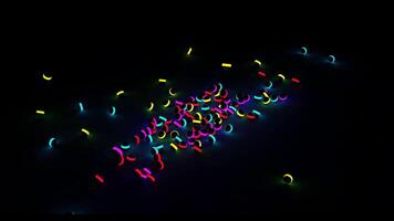 Many small dark balls with colorful neon stripe falling down and rolling into all the sides. Design. Small spheres with bright glowing lines isolated on a black background. video