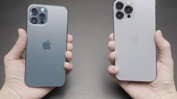 Paris - - Frankreich, 10.12.2021. männlich Hände halten und Vergleichen Neu iPhones 13 Profi max von Blau und Silber Farben. Aktion. wählen Neu modern Smartphone, Konzept von Marketing und Neu Technologien. video