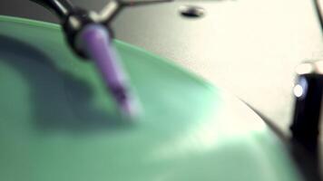 Stylus arm and needle lowered on turquoise vinyl record on a DJ turntable. Art. Close up of retro vinyl recorder under the lamp light. video