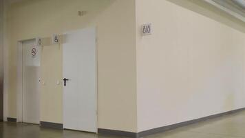 A washroom inside a shopping mall. HDR. Beige wall with white sign and silhouettes of man and woman at the public toilet. video