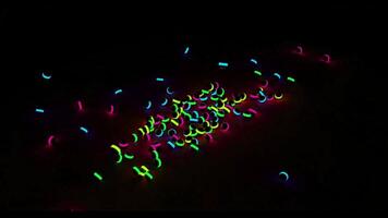 colorato splendente palle caduta e rotolamento su un' nero sfondo. design. molti nero bambini giocattolo palle con neon luci caduta su il pavimento. video