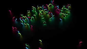 colorato splendente palle caduta e rotolamento su un' nero sfondo. design. molti nero bambini giocattolo palle con neon luci caduta su il pavimento. video