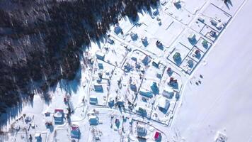 Winter bird's-eye view. Clip. Snowy winter sunny forest near residential small houses and large snowdrifts video