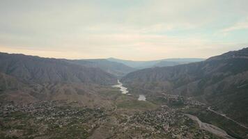 Aerial view of a bending river flowing above green high hills covered by haze. Action. Curving beautiful river and a picturesque valley, Indonesia. video