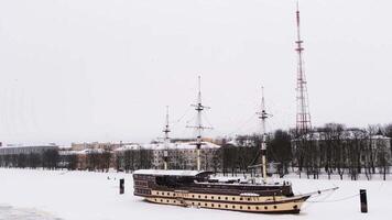 Floating restaurant Frigate Flagship on the Volkhov river on a winter day, Velikiy Novgorod. Concept. Beautiful retro stylized ship on a snow and ice covered river on cloudy sky background. video