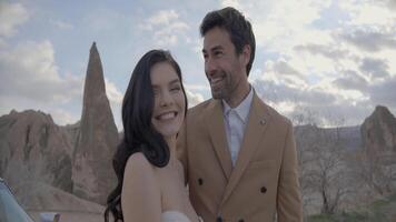 Couple smiling on background of canyon. Action. Elegant man and beautiful woman smile on background of rocks. Happy couple in elegant outfits happy on journey video