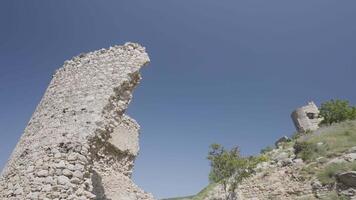 antico rovinato castello su il superiore di il collina su blu chiaro cielo sfondo. azione. rotto abbandonato pietra edificio su verde campo. video