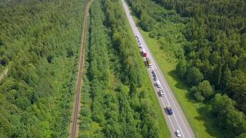 A huge highway with cars. Clip. The track is on the background of a green summer forest with huge trees on a summer day. video