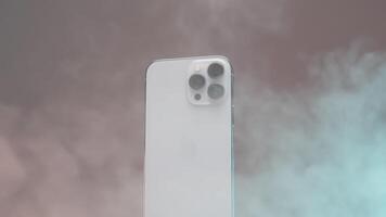 nieuw york - Verenigde Staten van Amerika, 10.11.2021. dichtbij omhoog van een nieuw iphone 13 pro max. hoogte met drie camera's. actie. stoom- verspreiden in de omgeving van een nieuw zilver smartphone roterend langzaam geïsoleerd Aan een beige muur achtergrond. video